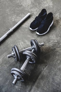 Beton yüzey üzerinde ayarlanabilir dumbell ve bar ile spor ayakkabı üstten görünüm