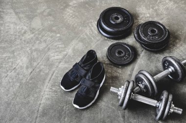 dumbell ağırlık plakaları ve spor ayakkabılar ile yüksek açılı görünüş beton zemin