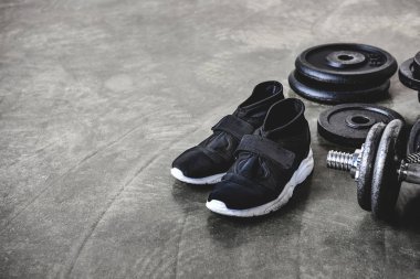 close-up shot of weight plates and sneakers on concrete floor clipart