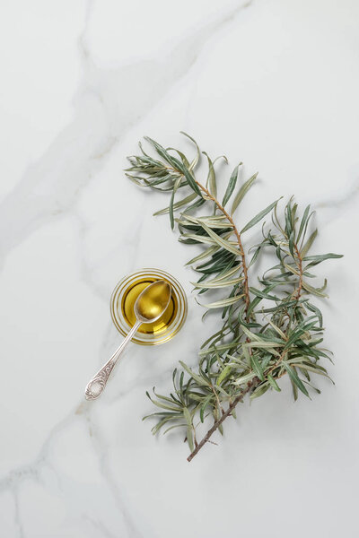 top view of olive oil and spoon in glass on marble table