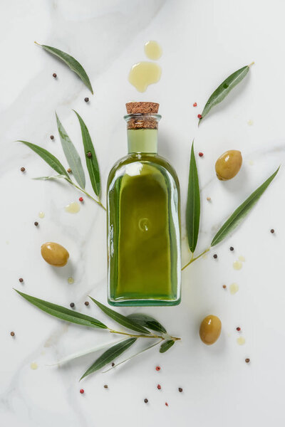 food styling of olive oil bottle and olives on marble table