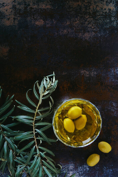 top view of olive oil and olives in glass on shabby surface