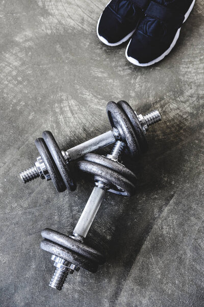 top view of adjustable dumbbells with sneakers on concrete surface