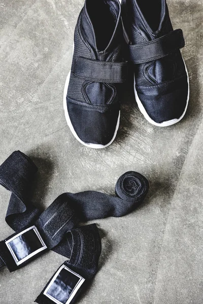 close-up shot of sneakers and wrist wraps on concrete surface