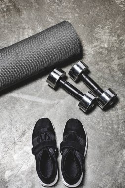 yoga mat ve beton yüzeyinde yalan dumbbells ile ayakkabı spor görünümünün yüksek açılı görünüş