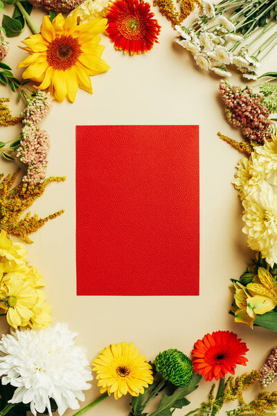 flat lay with various beautiful flowers and blank red card on beige background
