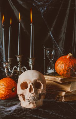 kafatası, kum saati, pumpkins, eski kitaplar ve siyah kumaş üzerine mumlar ile Pyres