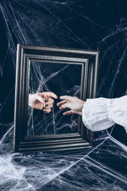 cropped view of woman touching to reflection in mirror with scary spider web around clipart