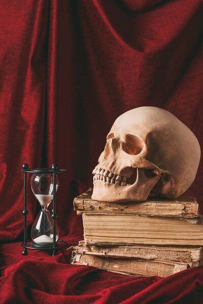 halloween skull on ancient books with hourglass on red cloth