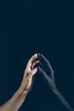 cropped view of woman touching with black demon hand isolated on black clipart