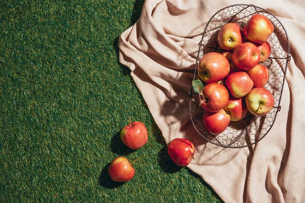 Κόκκινα Μήλα Μεταλλικό Καλάθι Για Λεηλασία Πανί Και Πράσινο Γρασίδι — Φωτογραφία Αρχείου