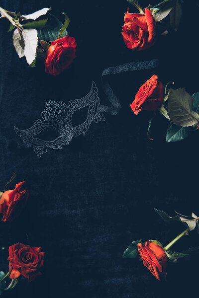 top view of lace mask and beautiful red roses on black background