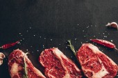 pohled ze syrové maso steaky a koření v kuchyni na povrchu
