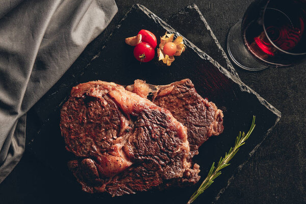 elevated view of roasted steaks on cutting boards, glass of red wine on tabletop in kitchen