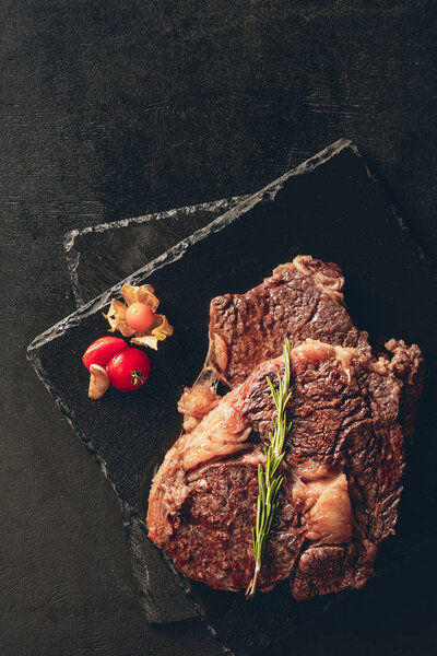 elevated view of roasted steaks with rosemary and berry on cutting boards in kitchen