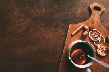 top view of homemade hot mulled wine with spices on cutting board on wooden background clipart