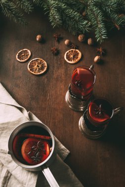 Tencere ve cam fincan kurutulmuş portakal dilimleri ve baharat ile ahşap arka plan üzerinde mulled şarap 