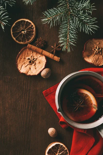 top view of traditional christmas mulled wine with dried apple slices and spices on wooden background