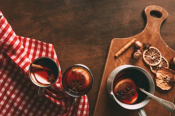 top view of glass cups with homemade mulled wine with spices on wooden background