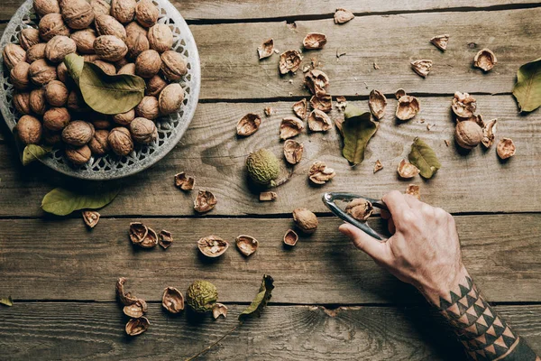 Cropped Shot Person Holding Nutcracker Wooden Table Walnuts Nutshells — Free Stock Photo