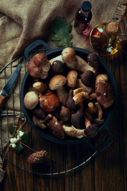 top view of fresh edible autumnal mushrooms in pan on wooden table   clipart
