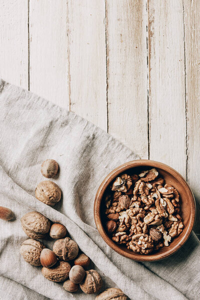 top view of hazelnuts and walnuts on cloth and plate on wooden table