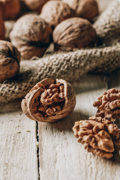 close-up view of whole and cracked walnuts and sackcloth on wooden table
