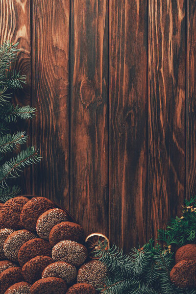 top view of tasty baked cookies and fir twigs on wooden table, christmas concept