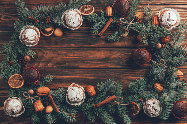 top view of tasty homemade baked muffins and fir twigs on wooden table, christmas concept