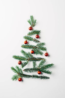 Beyaz arka plan üzerinde oyuncaklarla Noel ağacı düzenlenmiş çam dallarının üstten görünüm