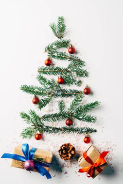 top view of green pine branch decorated as festive christmas tree with gifts and glitters on white background clipart