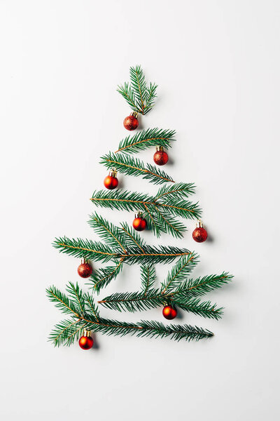 top view of pine branches arranged in christmas tree with toys on white background