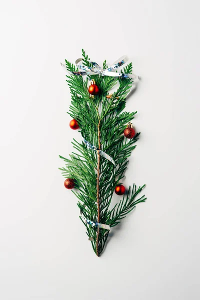 Top view of green pine branch decorated with christmas toys and ribbon as christmas tree on white backdrop — Stock Image Top View Green Pine Branch Decorated Christmas Toys Ribbon Christmas Stock Picture