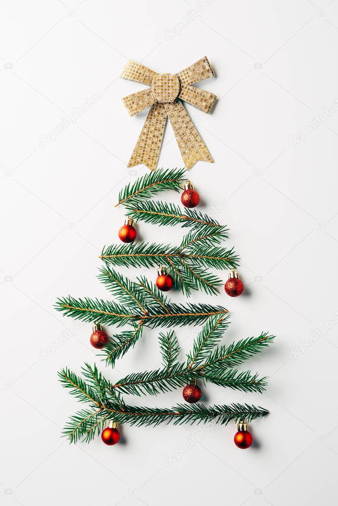 top view of green pine branch decorated as festive christmas tree with bow on white background