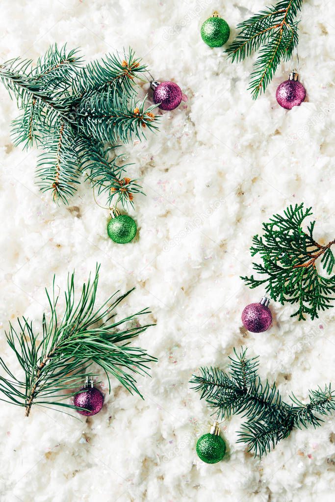 flat lay with pine tree branches, christmas toys on white cotton wool background