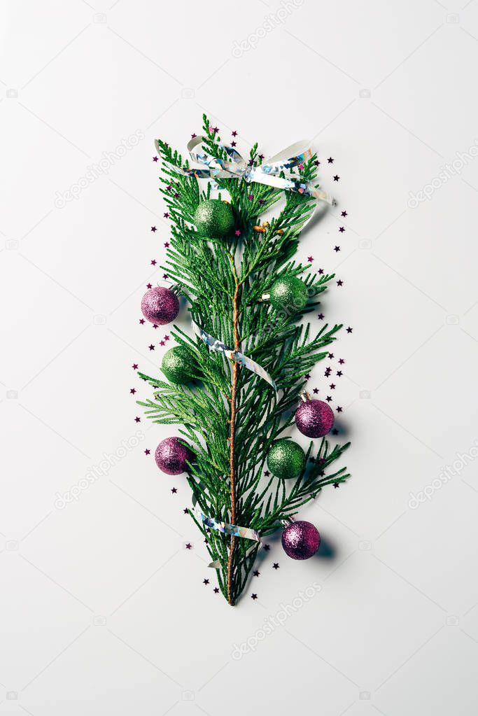 top view of green pine branch decorated with christmas toys as christmas tree on white backdrop