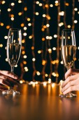 abgeschnittenes Bild eines Paares mit Champagnergläsern auf hellem Hintergrund, Weihnachtskonzept