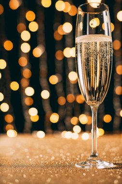one glass of champagne on garland light background, christmas concept clipart