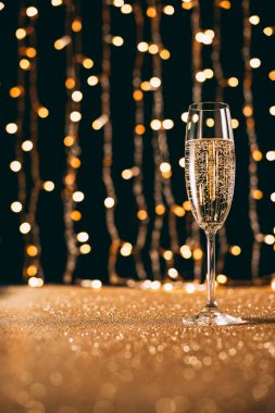surface level of one glass of champagne on garland light background, christmas concept clipart