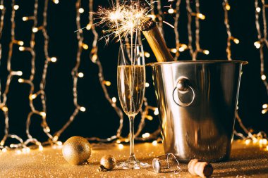 şampanya şişesi kova cam ile Noel çelenk ışık arka plan üzerinde parıldıyor.