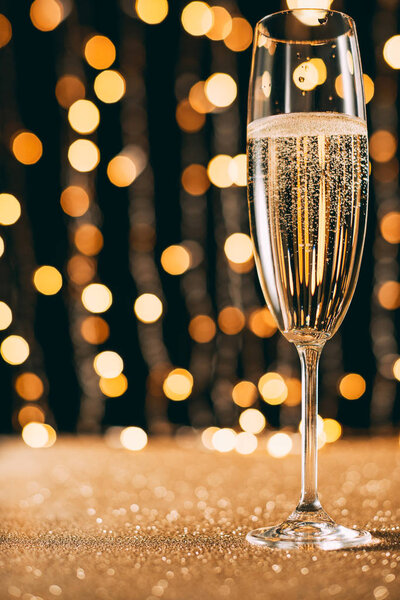 one glass of champagne on garland light background, christmas concept