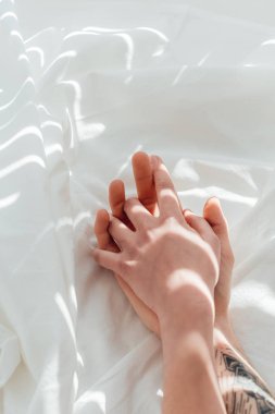beyaz çarşaf üzerinde yalan sırasında çift tutuşup sevgi dolu kısmi görünümü