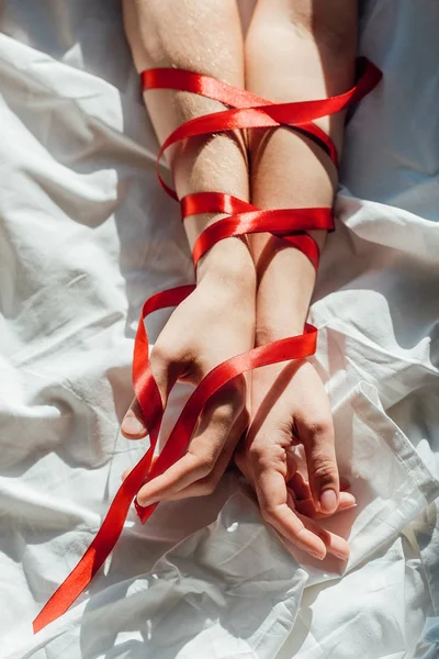Tiro Cortado Mãos Masculinas Femininas Amarradas Com Fita Vermelha Cama — Fotografia de Stock