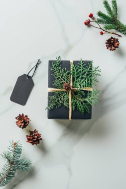 siyah Noel hediye kutusu çam dalları ve etiketi ile üstten görünüm mermer masada