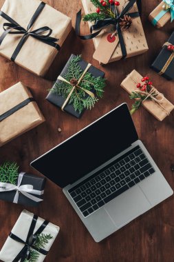 ahşap arka plan üzerinde Noel hediyeleri ve laptop ile boş perde üstten görünüm