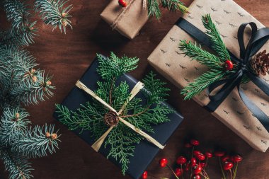 Noel hediye kutuları çam dalları ve dekoratif meyveleri ile üstten görünüm ahşap arka plan üzerinde  