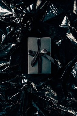 top view of gift box with black ribbon on black wrapping paper backdrop clipart