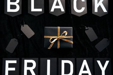 siyah zemin üzerinde siyah Cuma yazı, sarılmış hediye ve boş fiyat etiketleri üstten görünüm