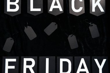 top view of black friday lettering and blank price tags on black background clipart