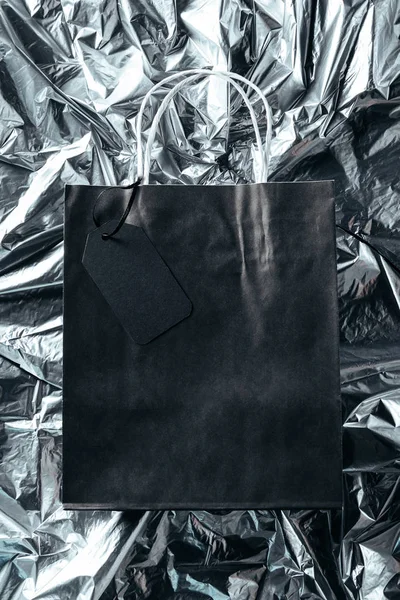 Вид Зверху Чорний Паперовий Мішок Порожнім Цінником Фоні Срібного Паперу — стокове фото